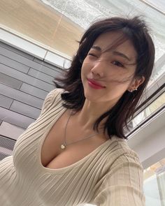 Woman with short hair winking and showing cleavage in a ribbed top