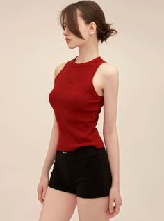 Woman in a red tank top and black shorts posing in profile