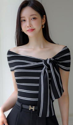Woman with long dark hair wearing a striped off-shoulder top and black belt