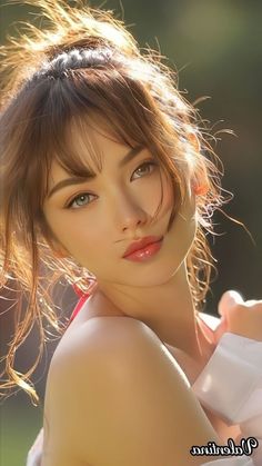 Woman with brown hair and red lipstick, exposed shoulder, soft lighting