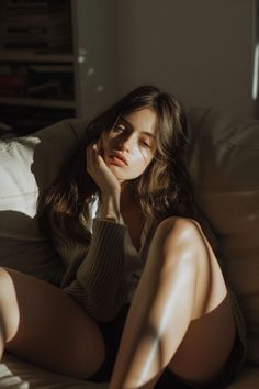 Woman with long hair in a sweater and shorts, bathed in warm sunlight indoors