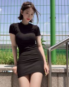 Woman in a black dress posing outdoors on a sunny day