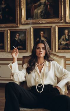Woman with long hair and pearl necklaces sitting in a chair, holding a cigarette