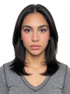 Woman with black layered hair and pink makeup against a white background