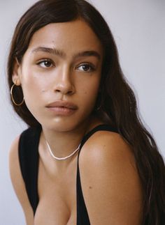 Woman with long dark hair wearing a black top and white choker