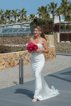 Woman in a white wedding dress holding a pink bouquet outdoors