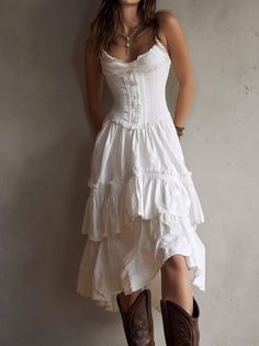 Woman in a white tiered dress with a corset top and cowboy boots