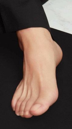 A bare foot against a dark background, with part of a black garment visible