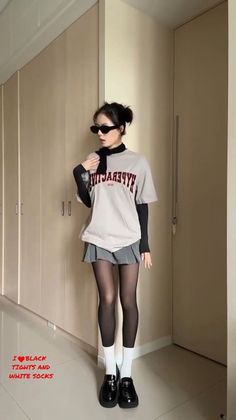 Woman in black tights, white socks, and a mini skirt posing indoors