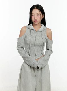 Woman with long black hair wearing a gray cropped hoodie and sweatpants