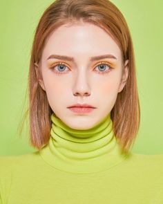 Woman with short hair and yellow eyeshadow wearing a lime green turtleneck