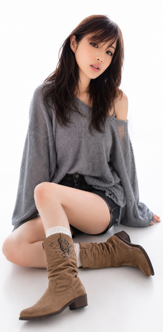 Woman in a gray sweater and denim shorts sitting on a white background