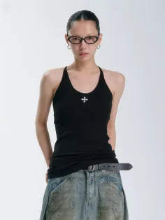 Woman in a black tank top and denim skirt with glasses and slicked back hair
