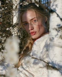 Blonde woman with a braid and freckles in a white dress outdoors