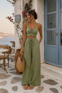 Woman in a green two-piece set holding a straw bag outdoors