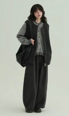 Woman with long hair wearing headphones, a cardigan, and wide leg pants