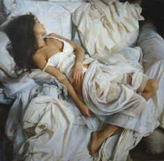 Woman with long hair lying on white sheets in a bedroom