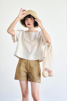 Woman in a straw hat and striped top holding a mesh bag