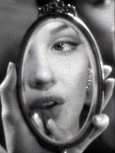 Woman's face reflected in a hand mirror, black and white photograph