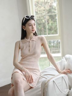 Woman in a pink dress with sunglasses on her head, sitting indoors