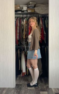 Woman in a denim skirt and cardigan standing in front of an open closet