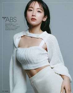 Woman in white knit crop top and cardigan with exposed midriff in a studio
