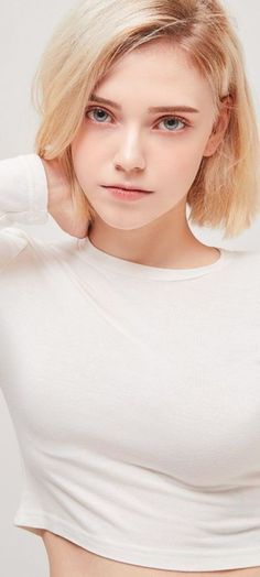 Woman with blonde hair and blue eyes wearing a white long-sleeved shirt