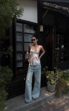 Woman in a satin camisole and wide leg jeans standing outdoors