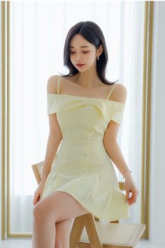Woman in a yellow off-shoulder dress sitting indoors with soft lighting