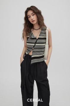 Woman with long wavy hair wearing a striped top and black pants indoors