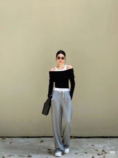 Woman in an off-shoulder top and sweatpants standing outdoors
