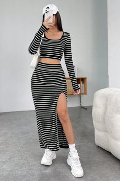 Woman in a black and white striped crop top and maxi skirt with a high slit