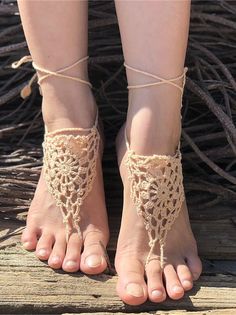 Pair of feet wearing crochet barefoot sandals on a wooden surface