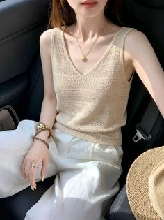 Woman in a knitted top and white pants sitting in a car