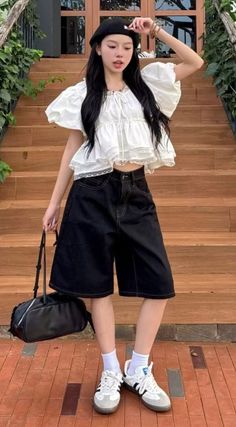 Woman in a white top, black shorts, and beret standing outdoors