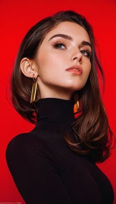 Woman in a black turtleneck and gold earrings against a red background