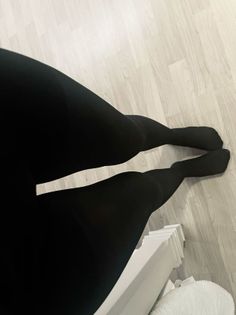 Person wearing black tights lying on a light wooden floor