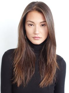 Woman with long dark hair wearing a black turtleneck against a white background