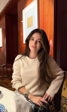 Woman with long brown hair wearing a cream sweater indoors