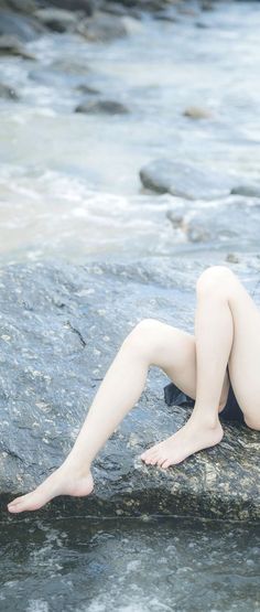 Bare legs and feet on a wet rock by the water