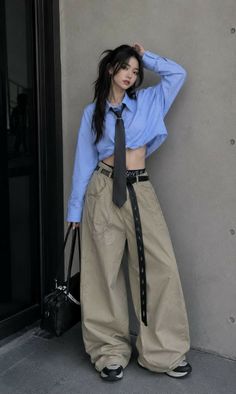 Woman in a cropped blue shirt and wide leg pants with a black tie