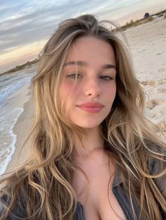 Woman with long blonde hair on a beach with ocean waves in the background