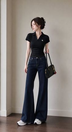 Woman in a black polo shirt and wide leg jeans holding a black handbag