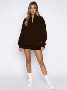 Woman in a brown quarter zip and shorts with white socks and sneakers