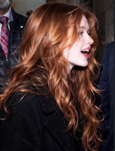 Woman with long red wavy hair smiling in profile view