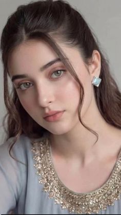 Woman with long brown hair and green eyes wearing an embroidered dress
