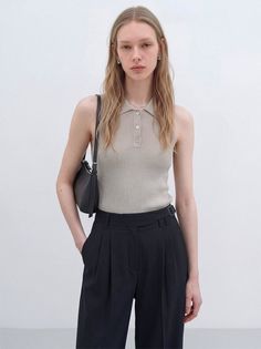 Woman with long blonde hair wearing a sleeveless top and pinstripe pants