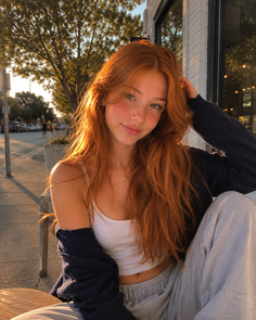 Young woman with red hair and freckles on a sunlit street at golden hour