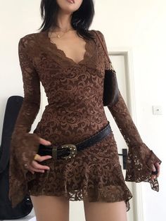 Woman in a brown lace dress with a black belt and shoulder bag
