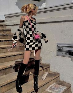 Woman in a checkered dress and knee-high boots on outdoor stairs